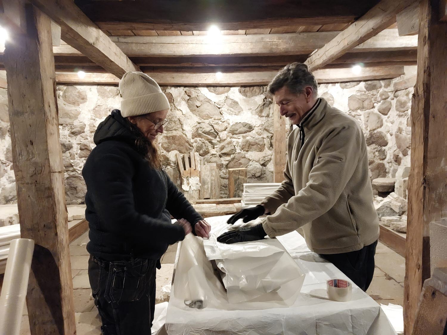 Föremål av sten, trä och järn flyttas från det medeltida stenhuset Rhyzeliusgården i Linköping till ett av museets magasin. Här ses konservatorerna Johanna Palm-Avis och Johan Roos.
