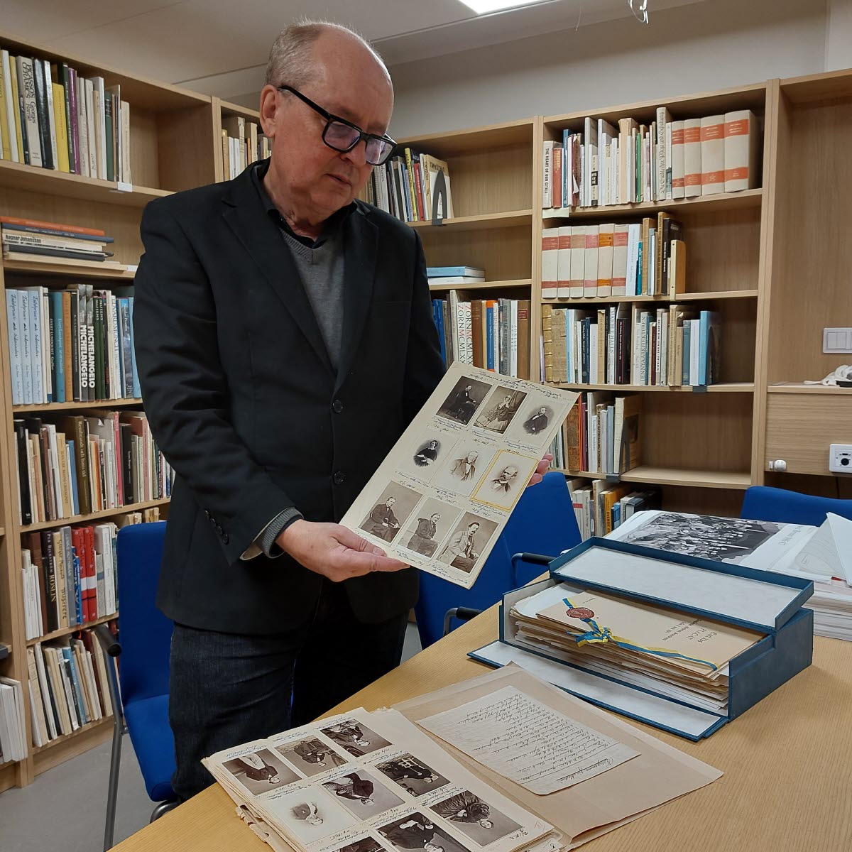 Arkivarie Jim Löfgren visar 1860-talsfotografier från Medevi brunn i Östergötlands museums arkiv och bibliotek.