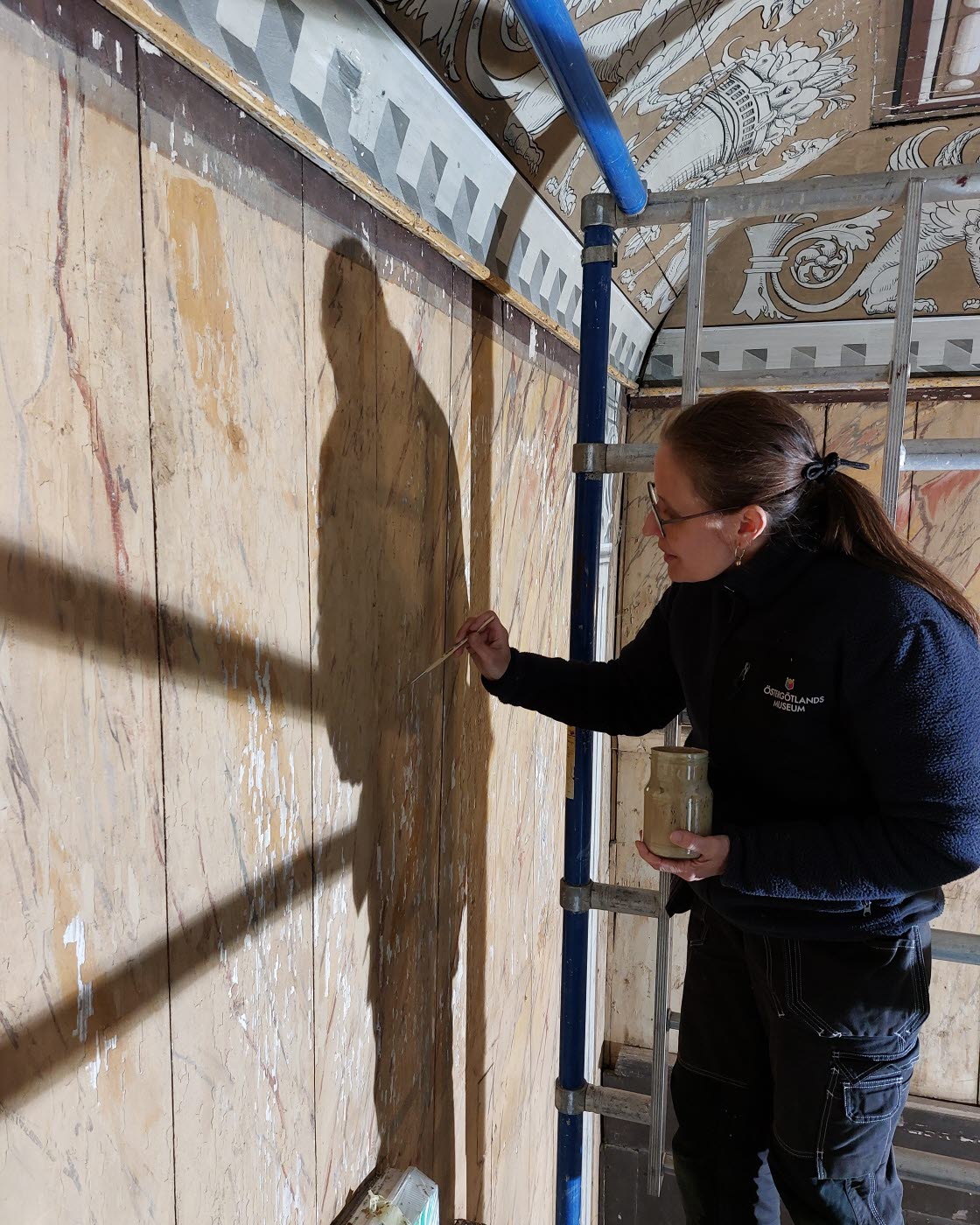 Museets konservatorer arbetar med väggmålningar från 1800-talet i Stora matsalen på Medevi Brunn. Konservator Johanna Palm-Avis.