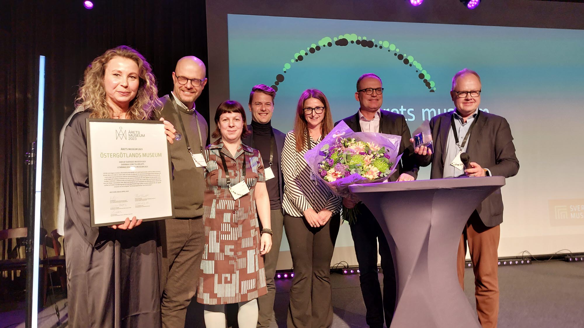 En grupp människor med diplom och blommor på en scen.