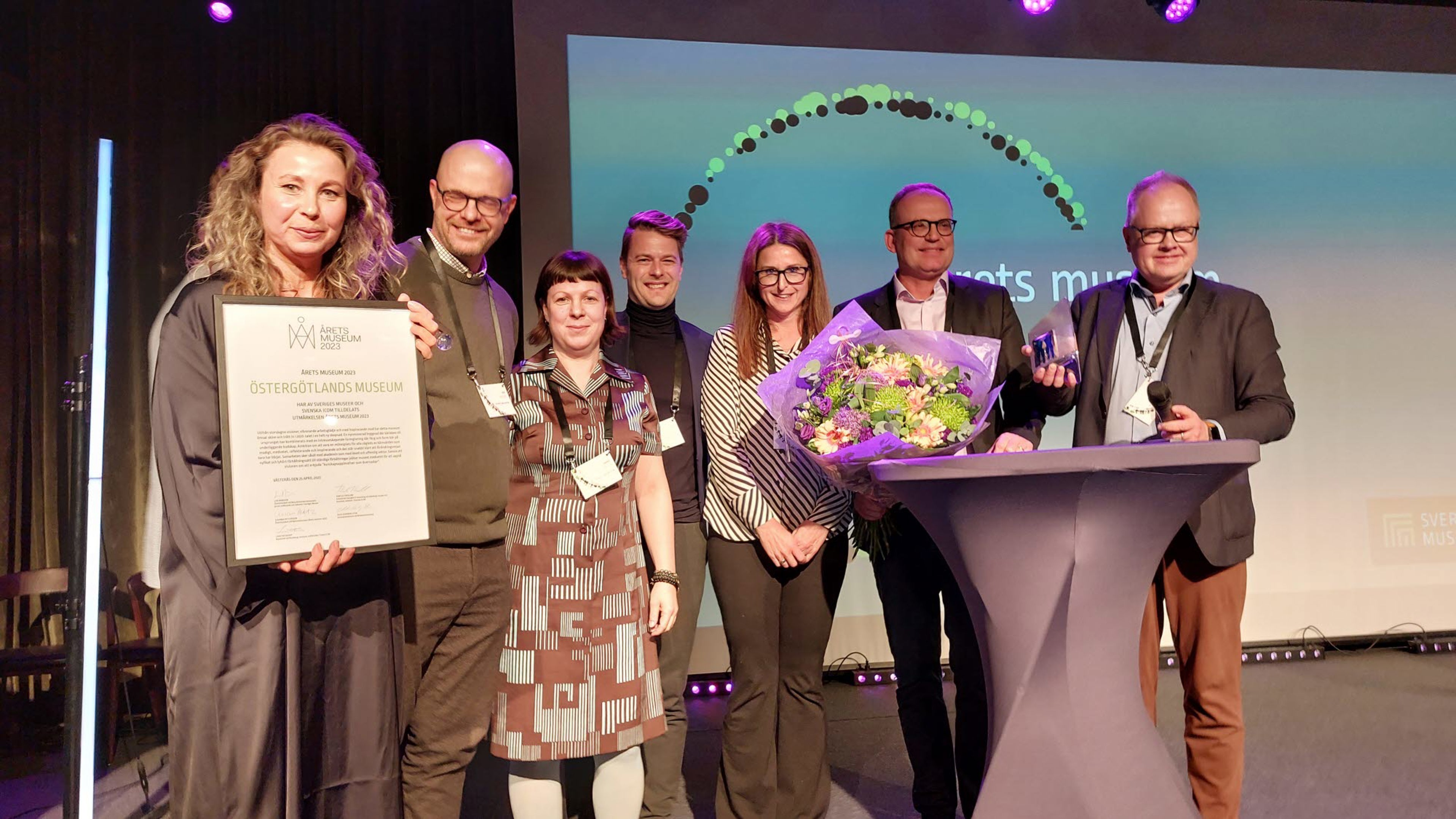 En grupp människor med diplom och blommor på en scen.
