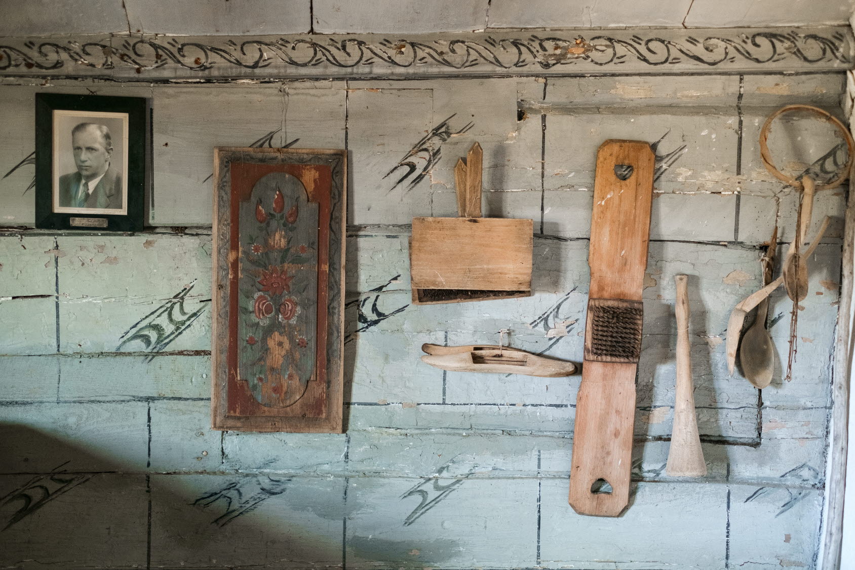 Närbild på vägg med olika redskap och en tavla 