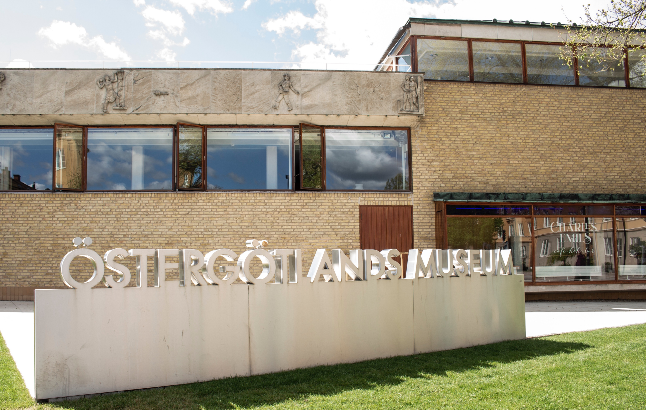 Gräsmatta och skylt "Östergötlands museum" framför museibyggnaden i Linköping.