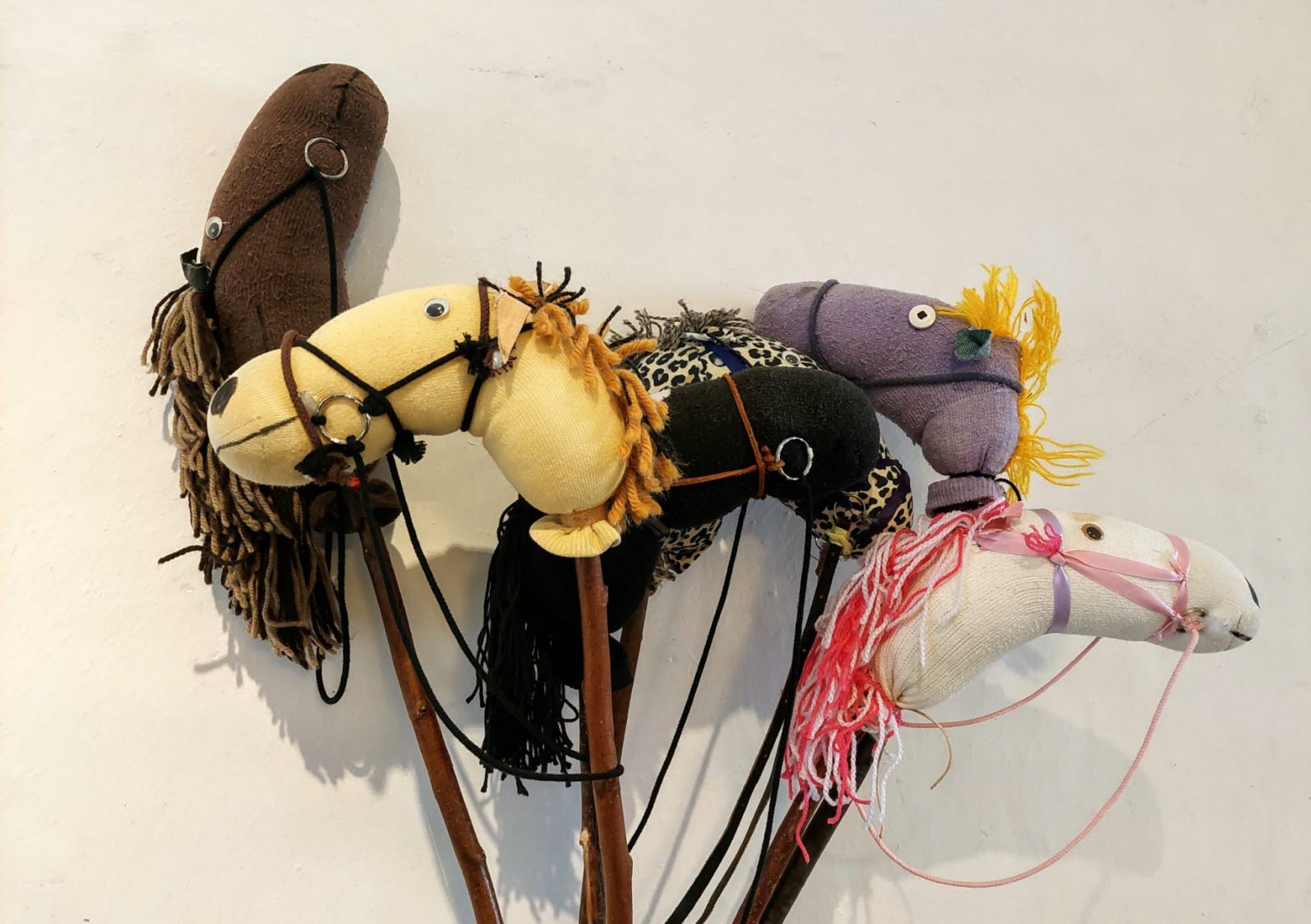 Fem handgjorda käpphästar står lutade mot en vägg.