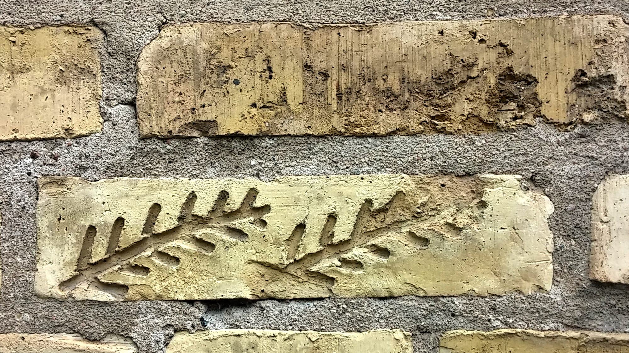 Museets gula tegelfasad med inristade krumelurer i en del tegelstenar.