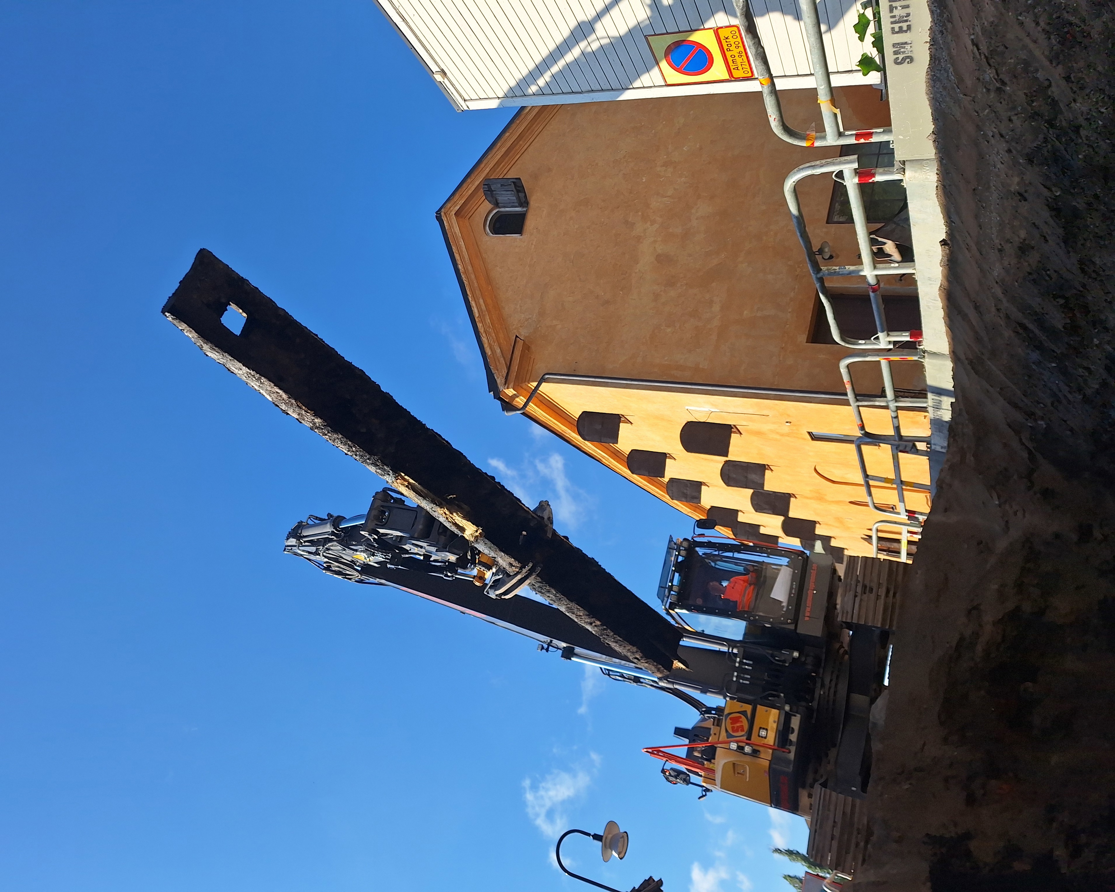 Träkonstruktionen (stocken) lyfts upp med hjälp av grävmaskin.