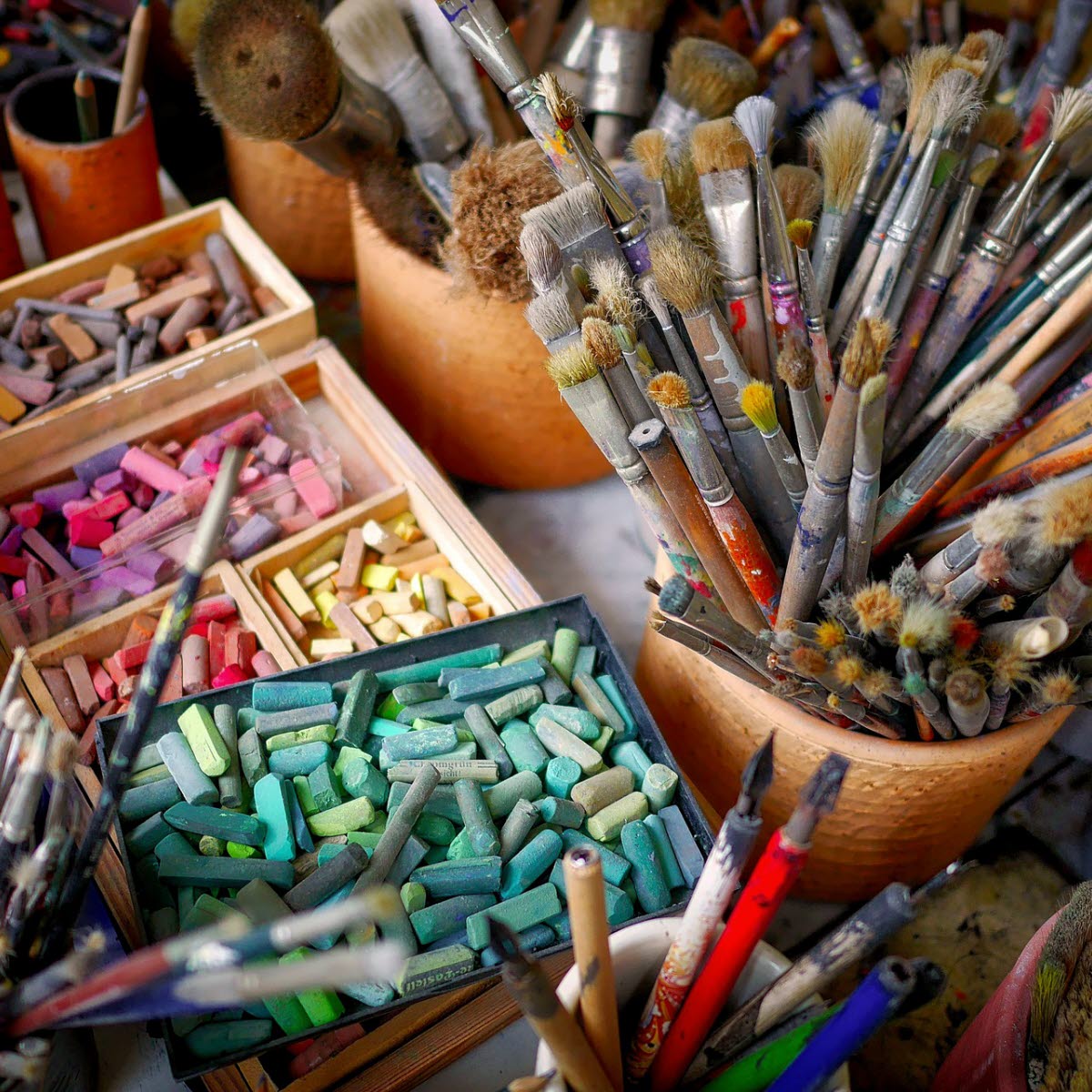 Mängder av konstnärsmateriel; penslar och kritor.