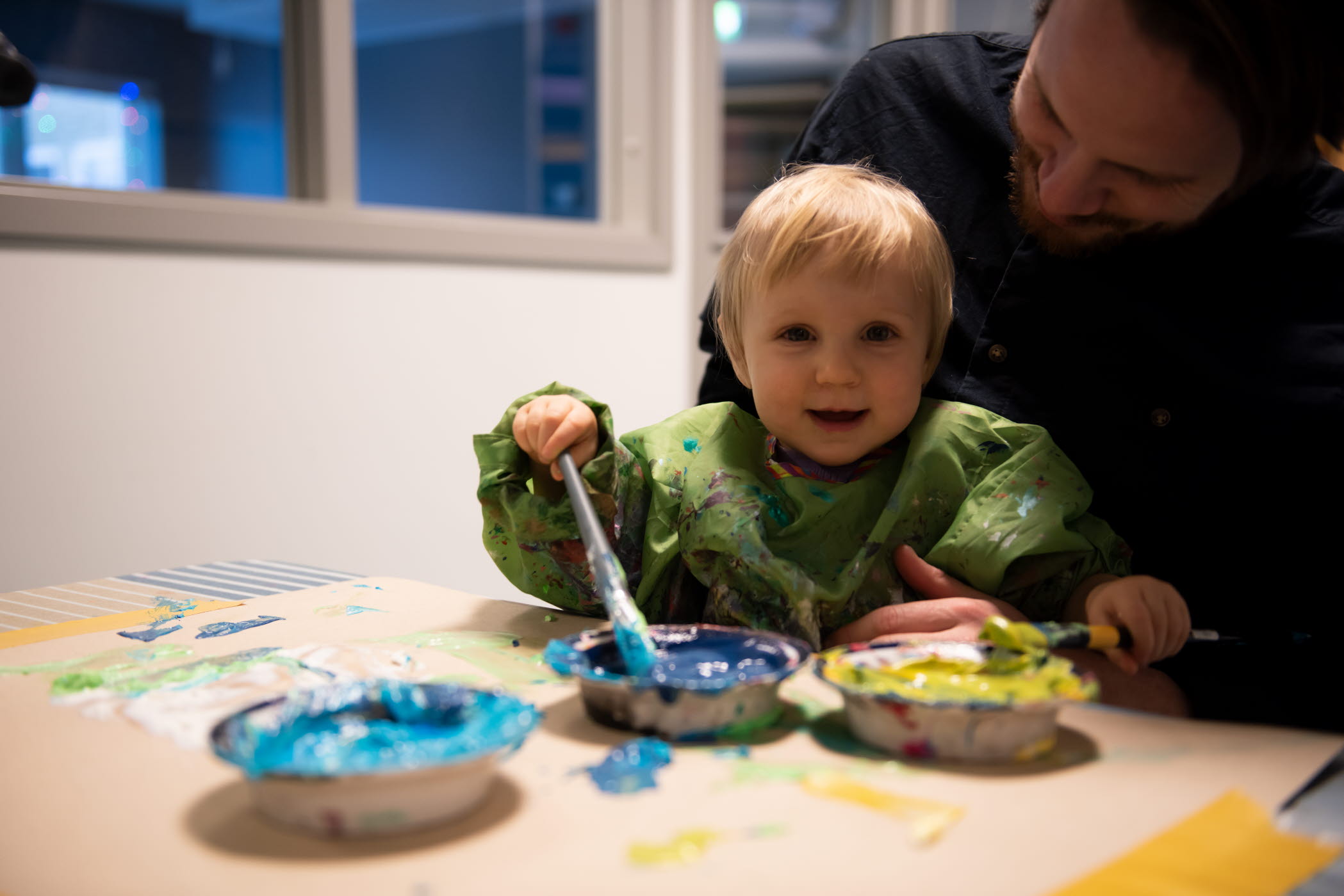 Ett barn som målar tillsammans med en vuxen. 