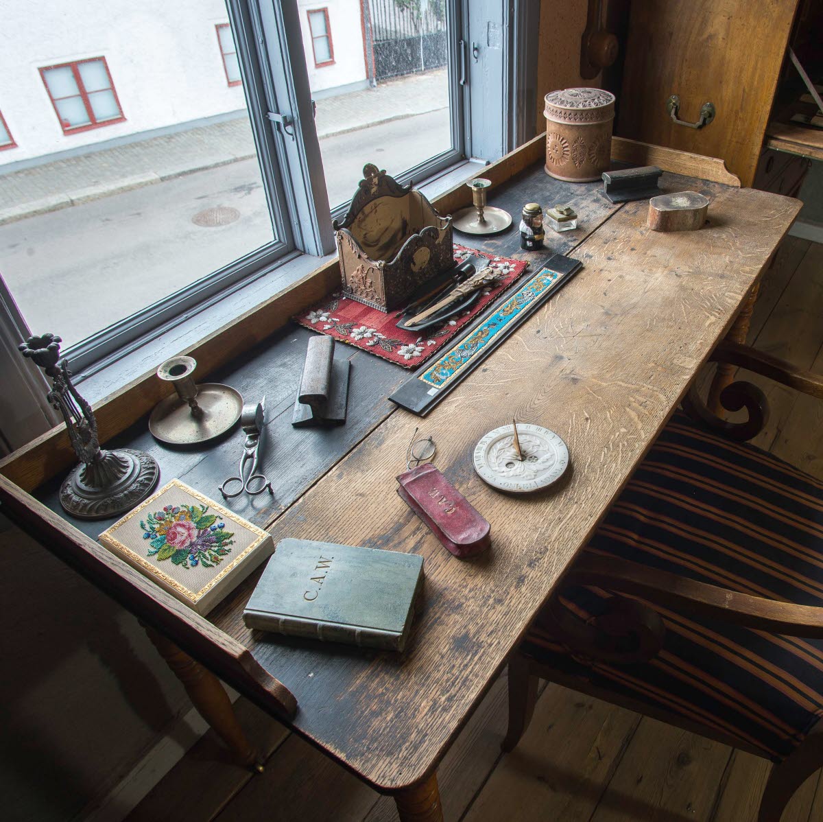 Interiör i museilägenheten i Onkel Adamsgården med bland annat ett skrivbord och en skrivbordsstol. Framför skrivbordet ett fönster med utsik mot huset på motstående sida av gatan.