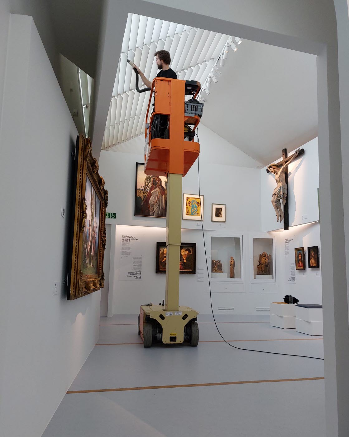 Museitekniker Sebastian Gustafsson dammsuger i konstutställningen Verkligheter.